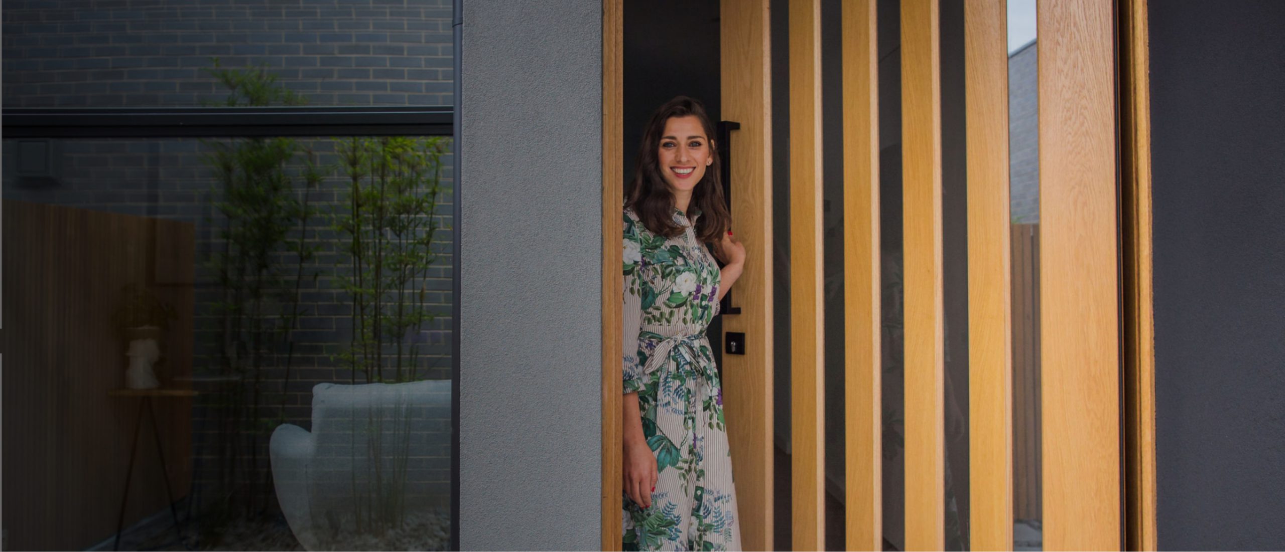 Smiling woman opening a timber front door