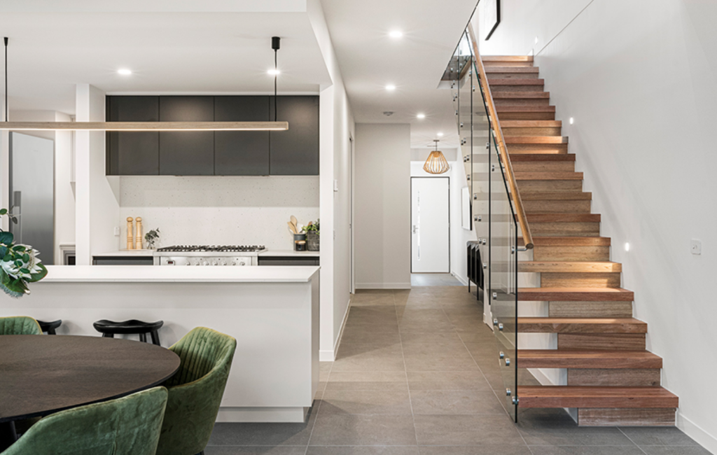 Modern kitchen and dining area with various light fixtures and timber staircase leading to a second floor