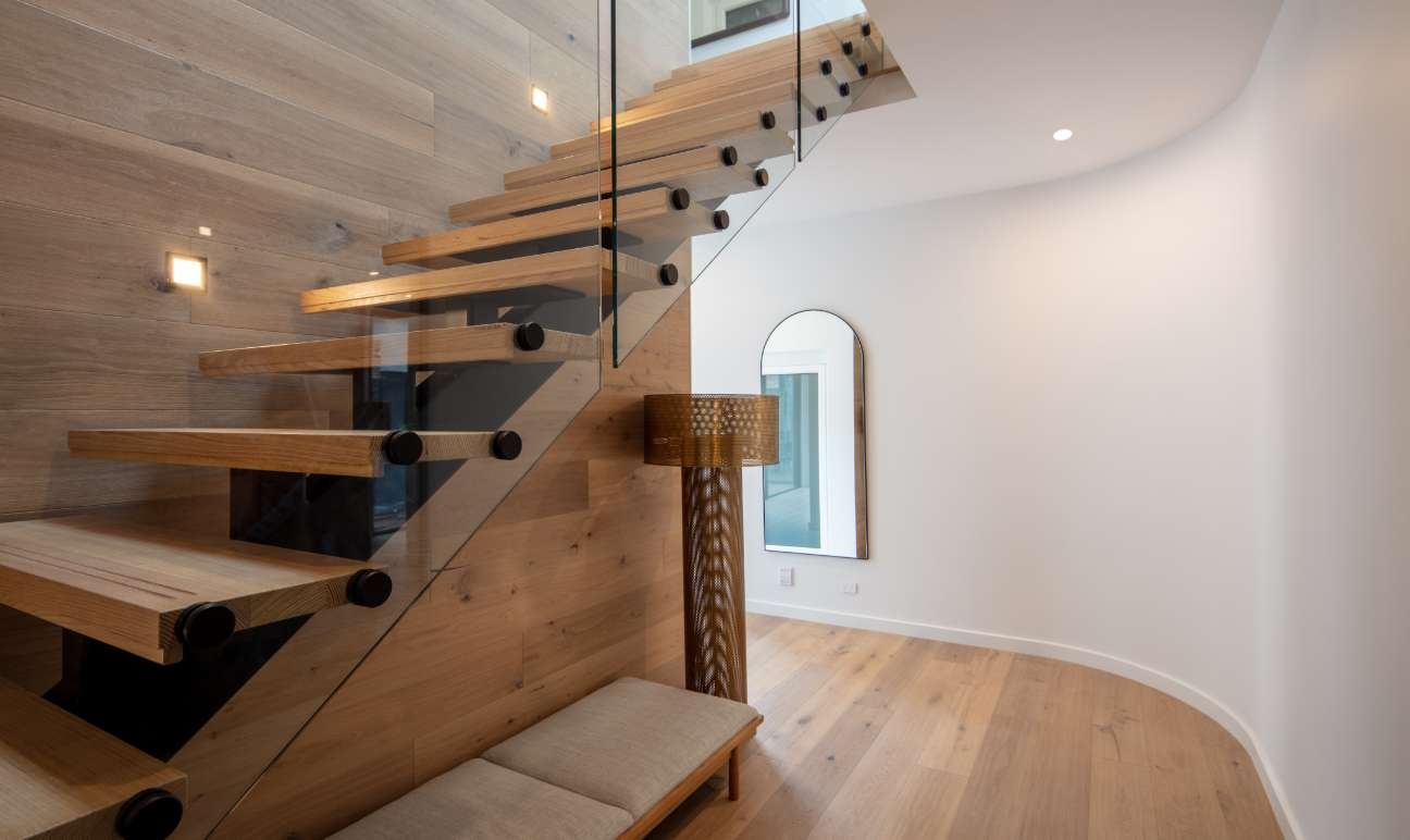 Timber staircase leading up from curved entry way