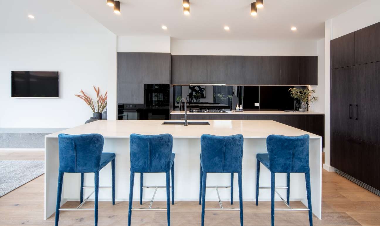 Modern kitchen with black cabinetry, white island and blue seating