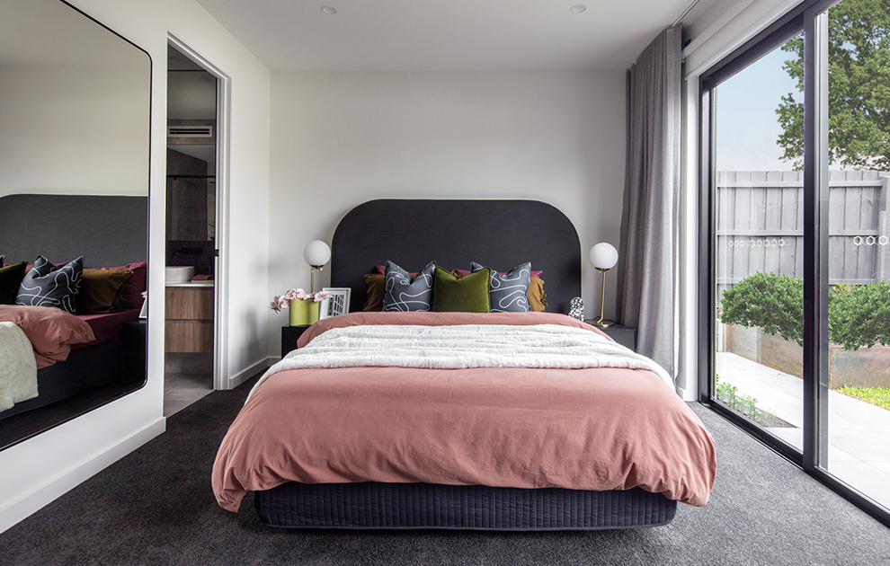 Bedroom with wall mirror and grey & pink bed linens