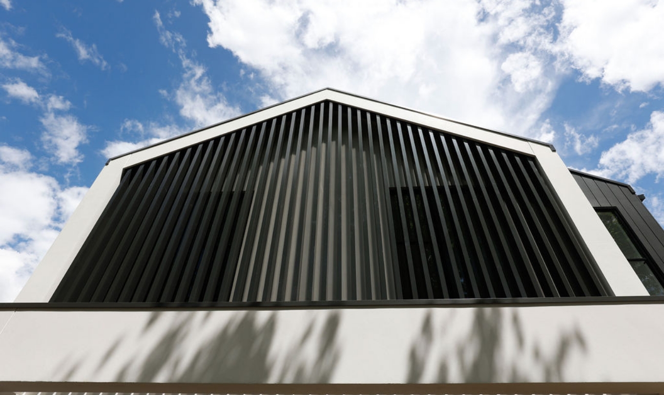 Black & white exterior against blue sky with clouds