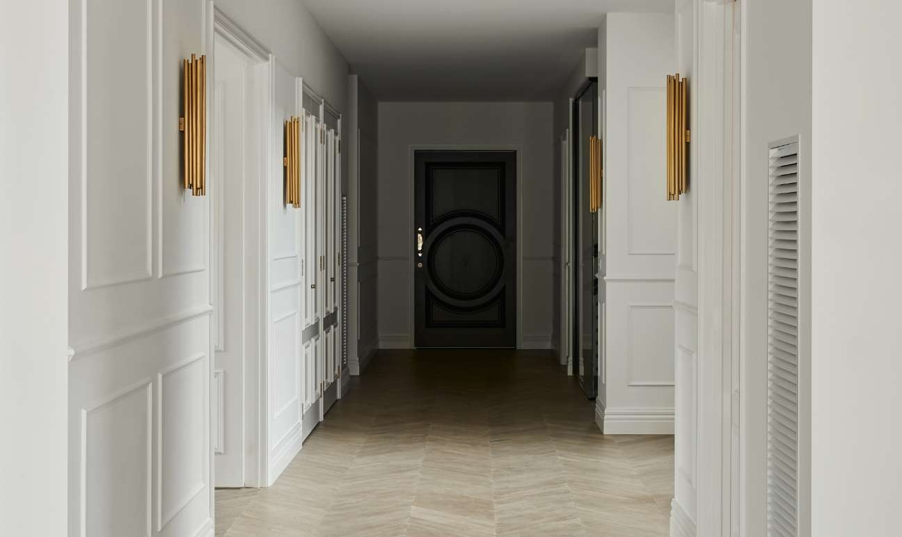 White hallway with trim and gold light fixtures
