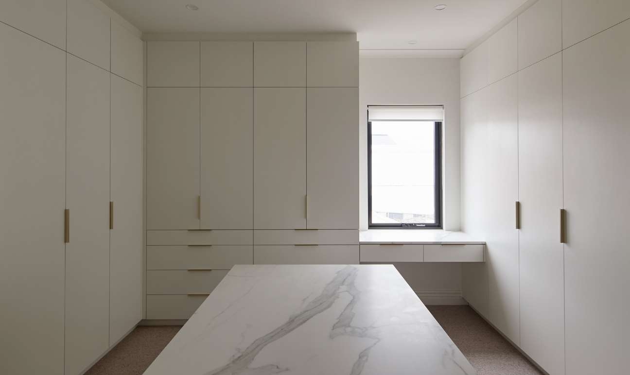 Custom dressing room with white cabinetry and stone top island