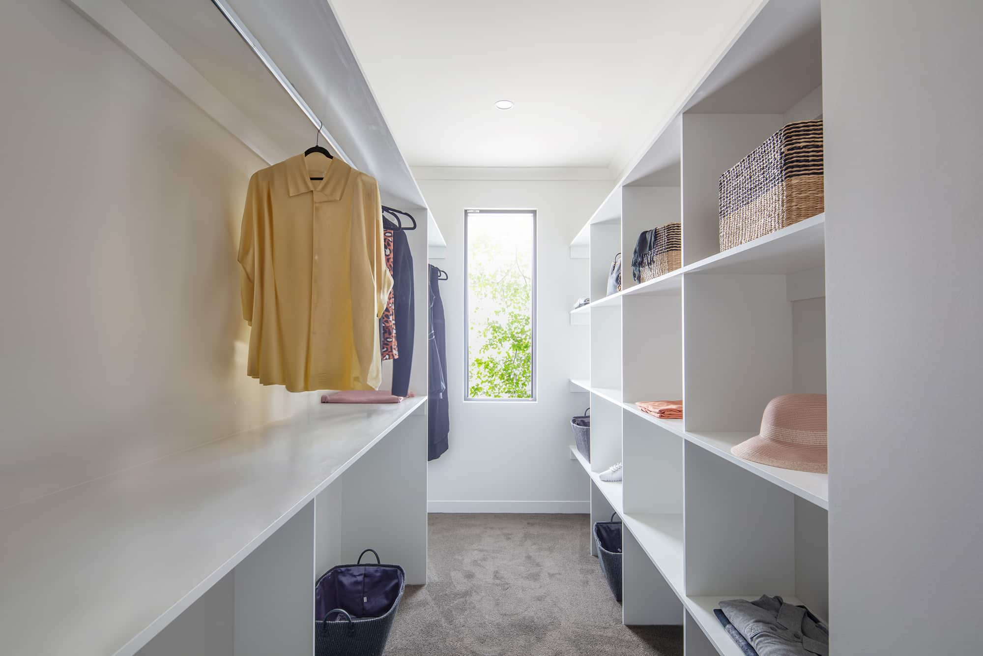 Walk-in wardrobe with white shelving and clothes hanging area