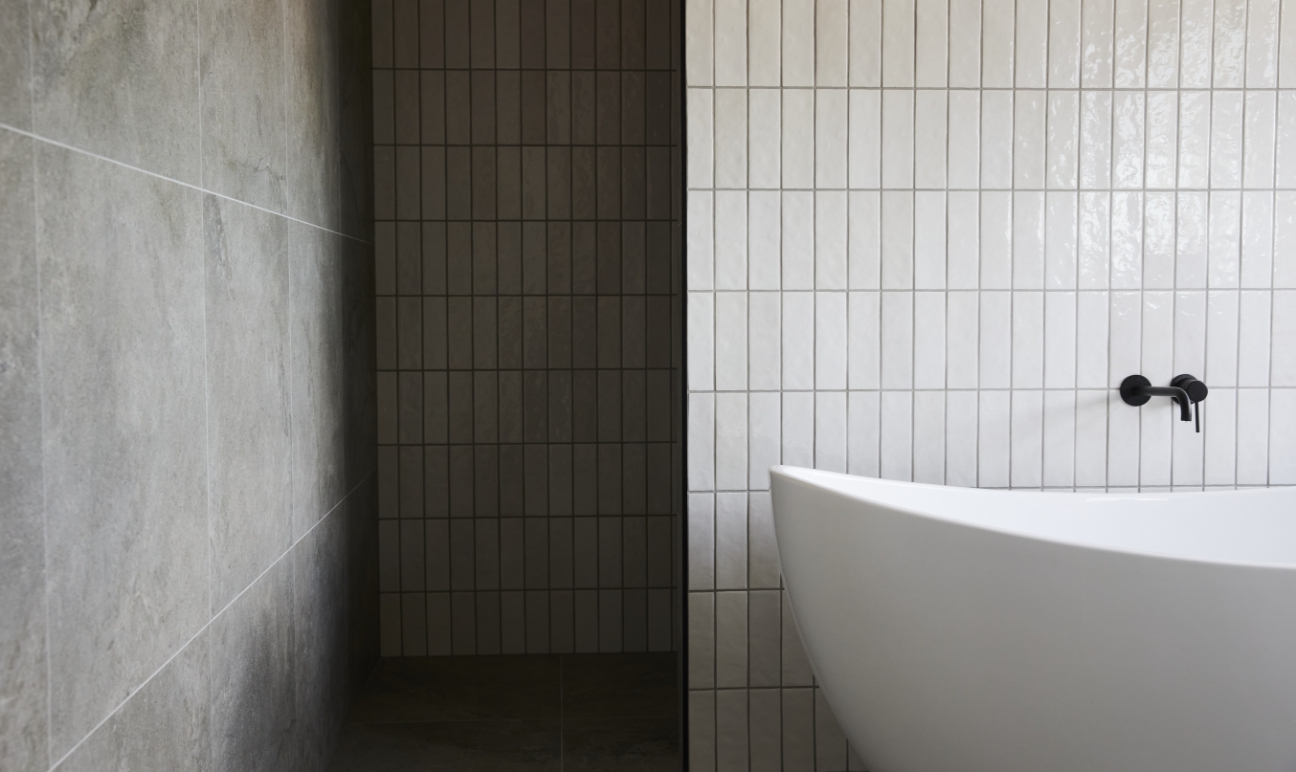 Modern bathroom with large white bath tub against vertical tiled wall