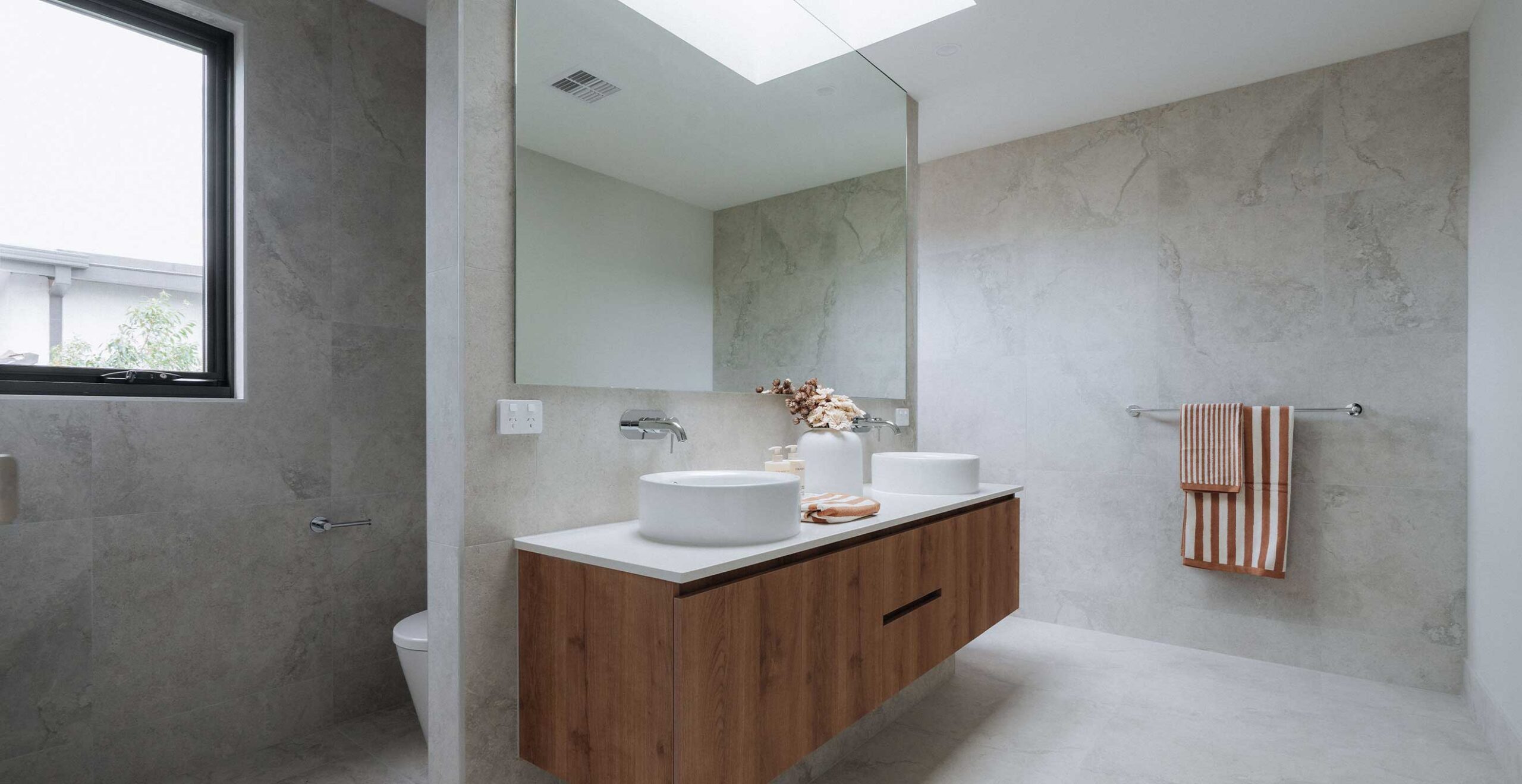 Modern bathroom with a double white vessel sink on a wooden floating vanity and a large mirror