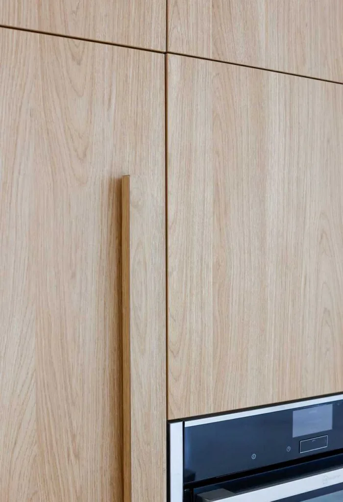 Light oak kitchen cabinetry with a tall vertical handle and a built-in oven at the lower right.