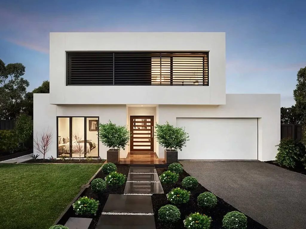 Modern white two‑story home with a wooden front door and landscaped front yard.