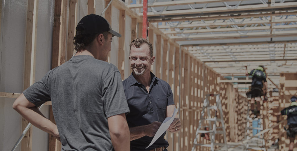 Two men on standing next to timber framing on building site