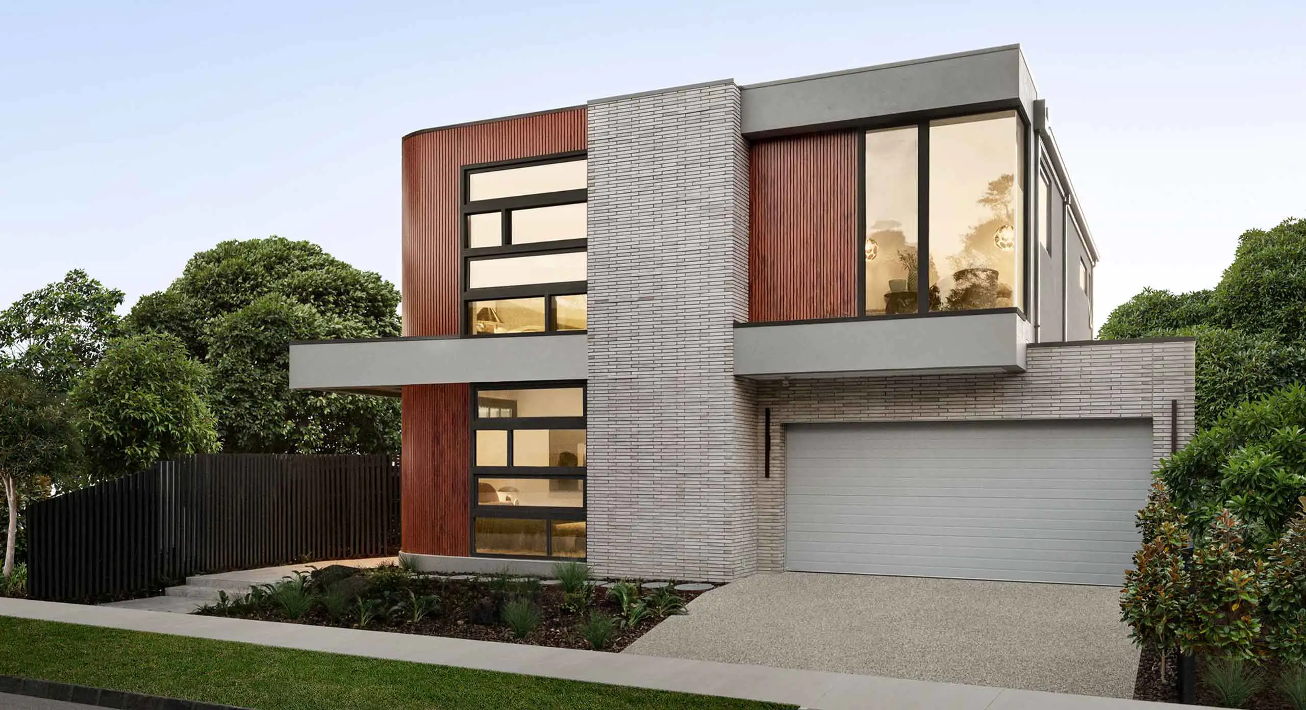 Modern two-story house with brick and wood siding, large windows, and a double garage.