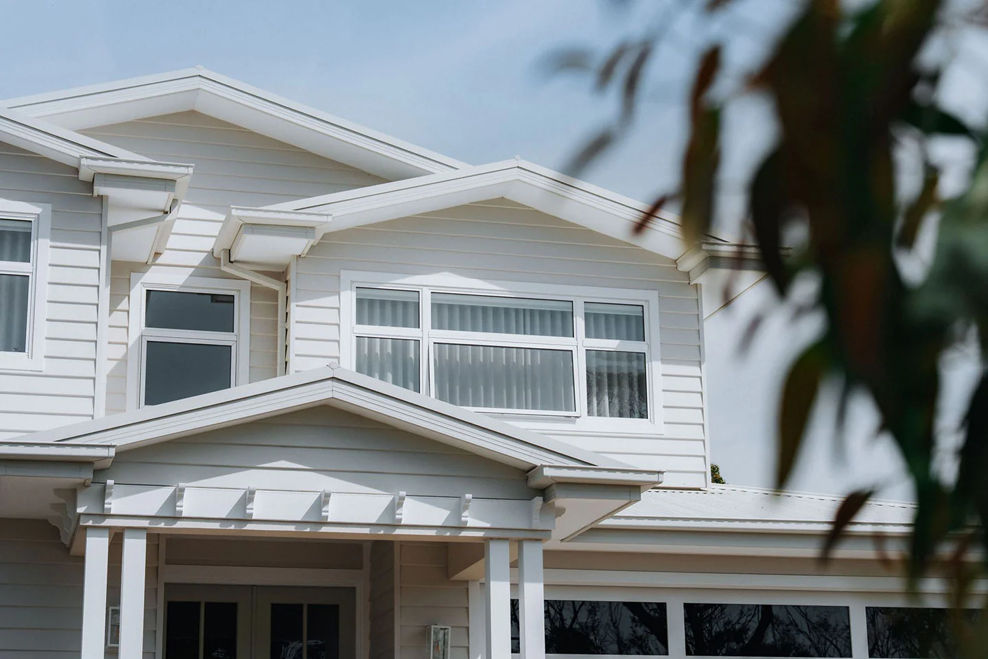 White two-story house with a gabled roof, white trim, and a front porch.